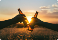 Zwei Hände stoßen mit Bierflaschen an